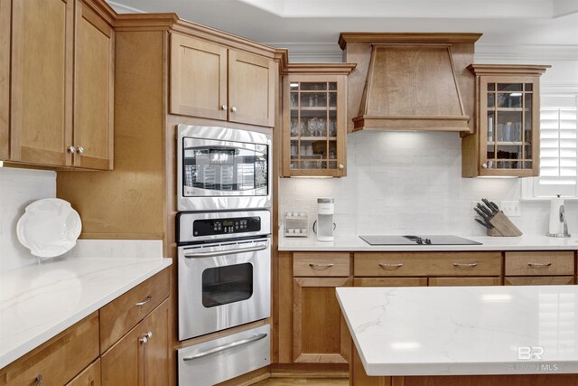 kitchen featuring tasteful backsplash, a warming drawer, stainless steel microwave, premium range hood, and black electric stovetop