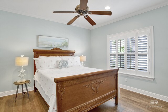 bedroom featuring a ceiling fan, wood finished floors, baseboards, and ornamental molding