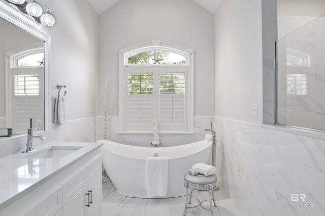 bathroom with vanity, tile walls, a soaking tub, a wainscoted wall, and marble finish floor