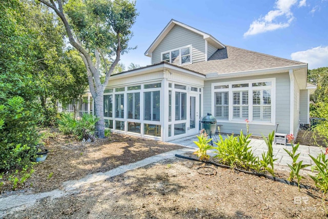 rear view of house with a sunroom and roof with shingles