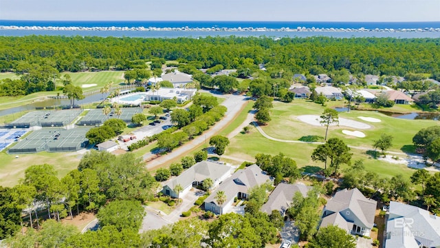 drone / aerial view with a water view, golf course view, and a wooded view