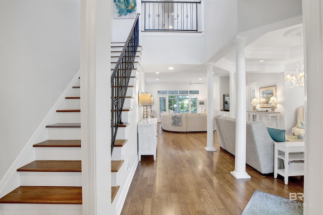 entryway with ornate columns, recessed lighting, wood finished floors, a high ceiling, and stairs