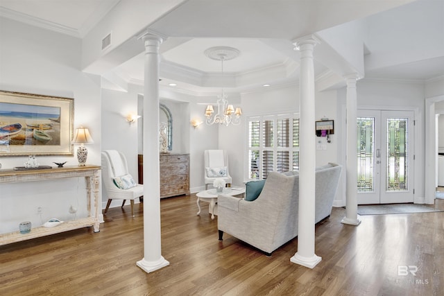 living area featuring wood finished floors, ornamental molding, visible vents, and a wealth of natural light