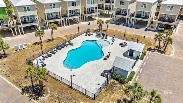 community pool with a patio, fence, and a residential view