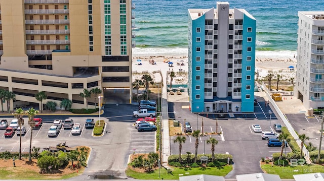 view of property with a view of the beach, uncovered parking, and a water view