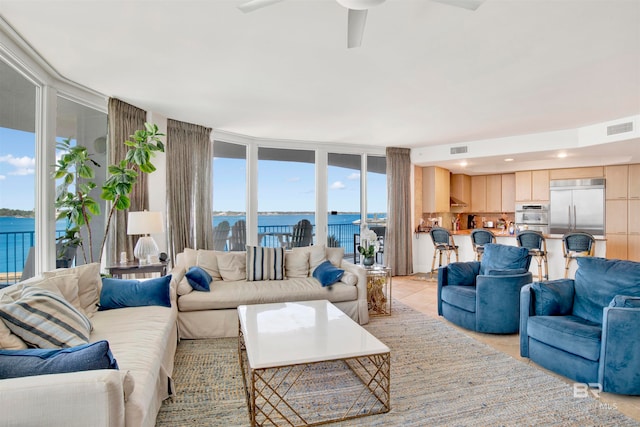 living room with a wealth of natural light, a water view, and light tile patterned floors