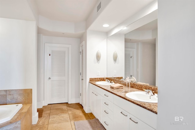 bathroom with tiled tub, tile patterned flooring, and vanity