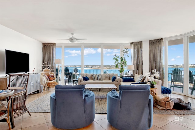 tiled living room featuring ceiling fan, a water view, a healthy amount of sunlight, and a wall of windows