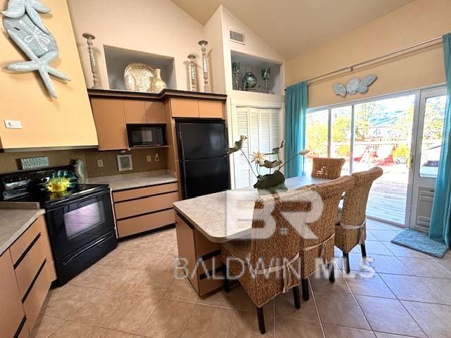 kitchen with lofted ceiling, black appliances, and light tile patterned floors