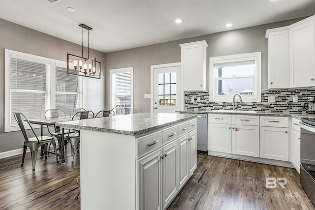 kitchen featuring a kitchen island, sink, white cabinets, and decorative light fixtures