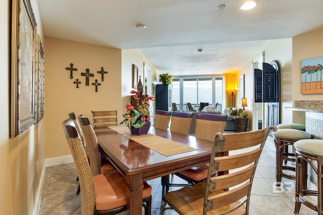 dining room featuring light tile patterned floors, a textured ceiling, and baseboards