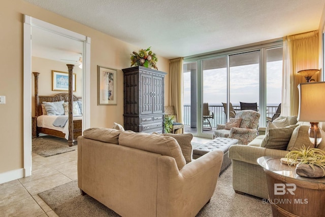 living room featuring light tile patterned floors, baseboards, floor to ceiling windows, and a textured ceiling