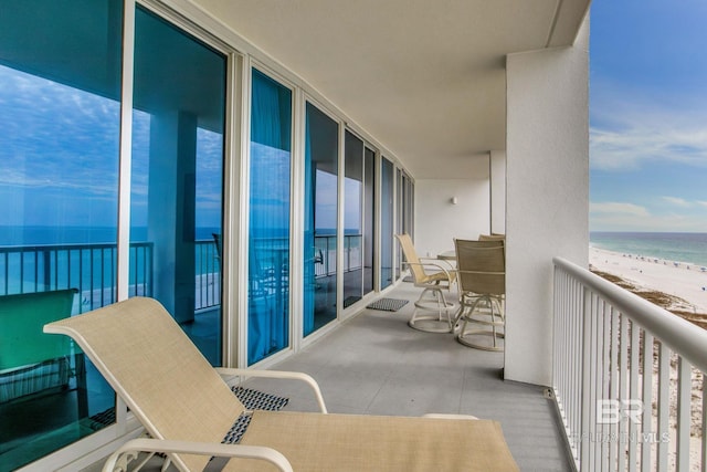 balcony featuring a view of the beach and a water view