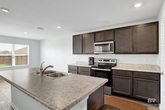 kitchen featuring stainless steel appliances, a kitchen island with sink, sink, and dark brown cabinetry