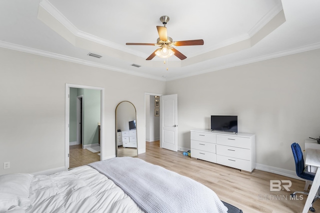 bedroom featuring light wood-type flooring, a tray ceiling, visible vents, and crown molding