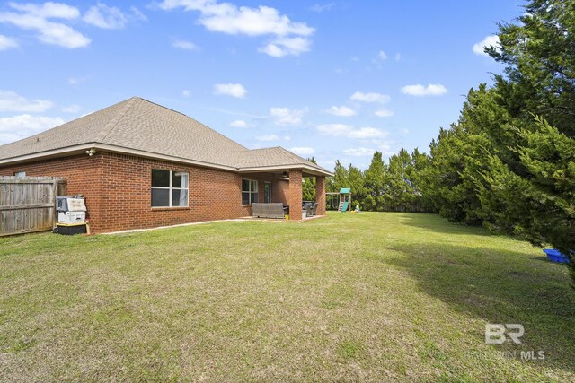 rear view of house with a yard, fence, brick siding, and a playground