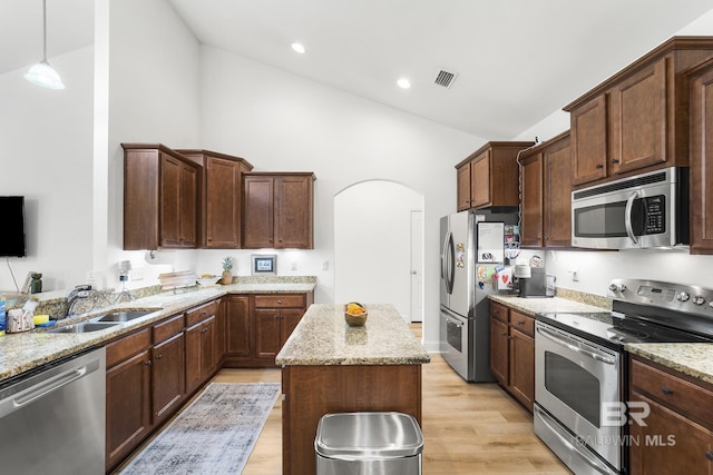 kitchen with light stone counters, visible vents, arched walkways, a sink, and appliances with stainless steel finishes