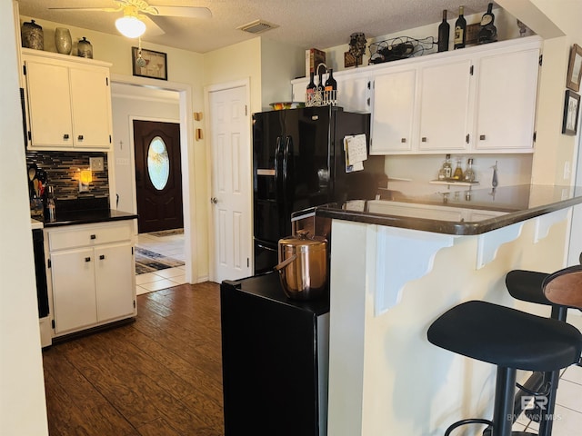 513 3rd St, Fairhope, AL 36532 - kitchen featuring black refrigerator with ice dispenser, dark countertops, a ceiling fan, dark wood finished floors, and white cabinetry