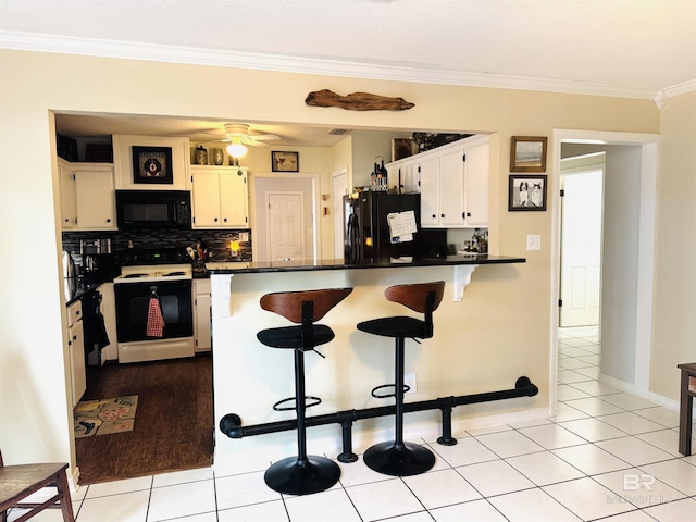 513 3rd St, Fairhope, AL 36532 - kitchen featuring black appliances, a peninsula, ornamental molding, dark countertops, and a kitchen breakfast bar