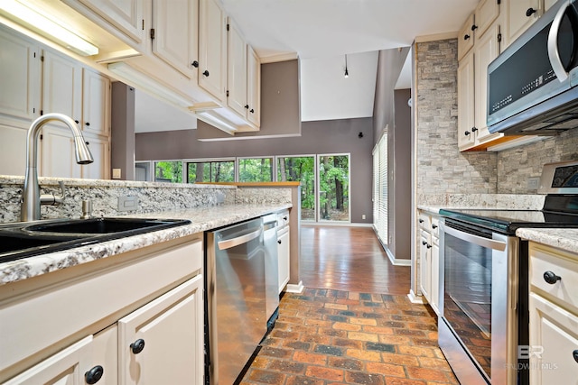 6 Pirates Ln, Spanish Fort, AL 36527 - kitchen with stainless steel appliances, backsplash, brick flooring, and white cabinetry