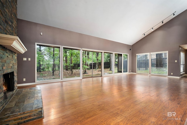 6 Pirates Ln, Spanish Fort, AL 36527 - unfurnished living room featuring high vaulted ceiling, a large fireplace, track lighting, healthy amount of natural light, and wood finished floors