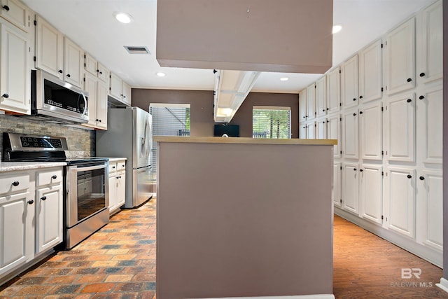 6 Pirates Ln, Spanish Fort, AL 36527 - kitchen with appliances with stainless steel finishes, backsplash, white cabinetry, recessed lighting, and a center island