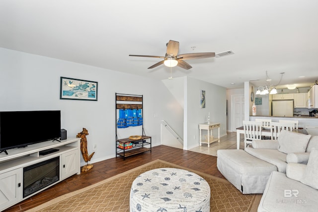 living room featuring ceiling fan with notable chandelier and hardwood / wood-style flooring