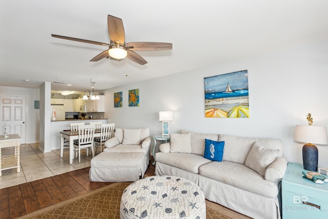 living room with ceiling fan with notable chandelier and light wood-type flooring