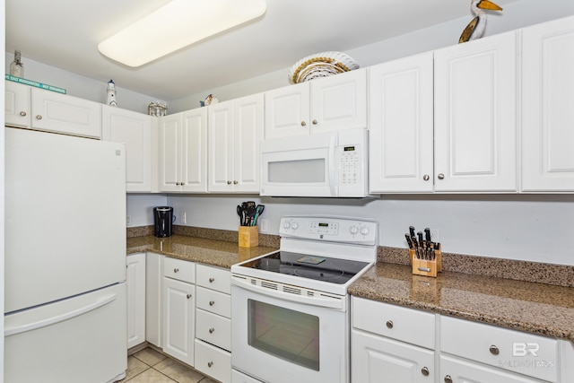 kitchen with dark stone countertops, light tile patterned floors, white appliances, and white cabinets