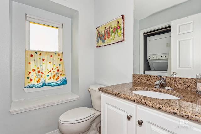 bathroom with vanity, toilet, and stacked washing maching and dryer