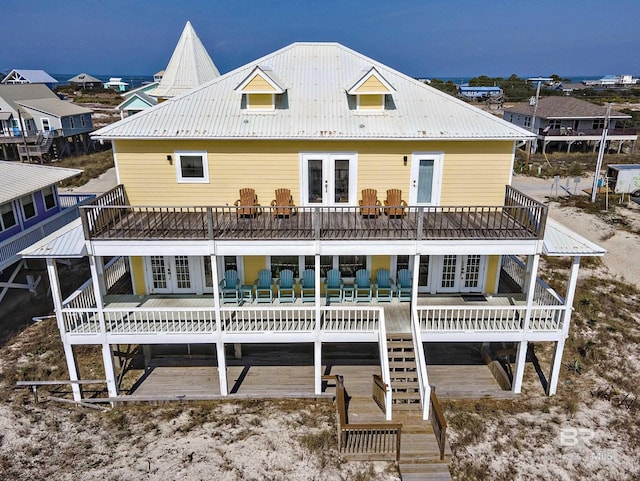 back of house with a balcony, a wooden deck, metal roof, and french doors