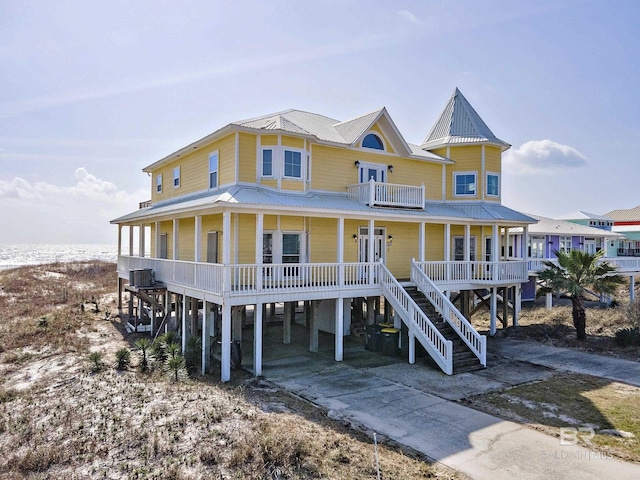 view of front of home with driveway, metal roof, covered porch, cooling unit, and french doors