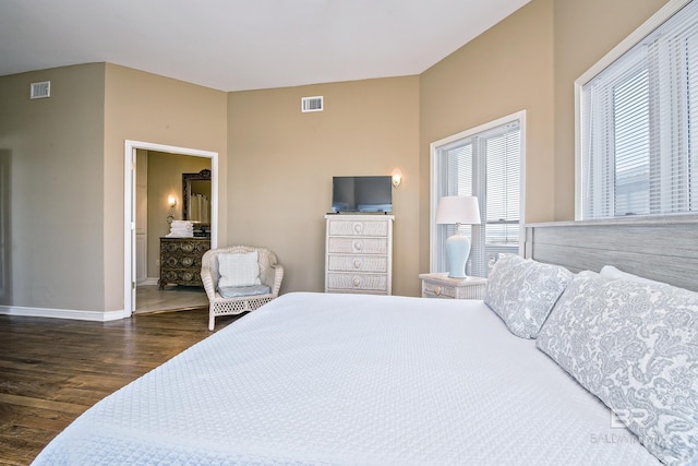 bedroom with dark wood-type flooring, connected bathroom, visible vents, and baseboards