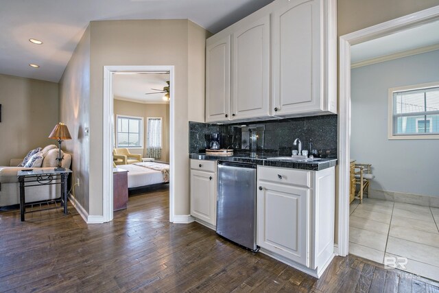 kitchen featuring white cabinets, tile countertops, dark wood-style floors, a sink, and backsplash