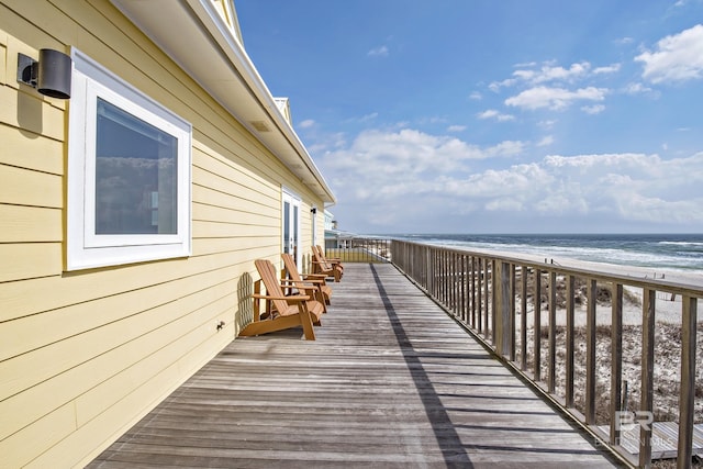 wooden terrace featuring a water view and a view of the beach