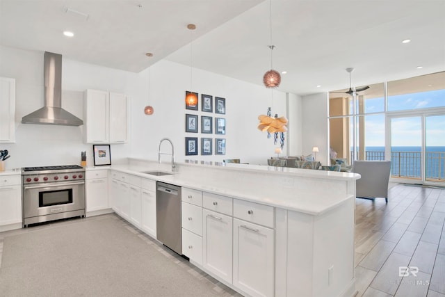 kitchen with white cabinets, kitchen peninsula, wall chimney exhaust hood, stainless steel appliances, and a water view