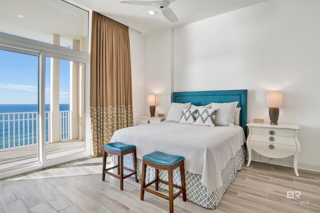 bedroom featuring light hardwood / wood-style floors, a water view, ceiling fan, and access to exterior