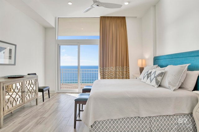 bedroom featuring light wood-type flooring, a water view, ceiling fan, and access to exterior