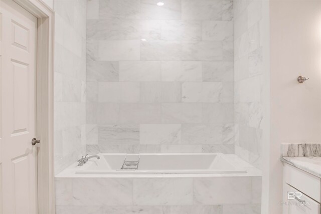 bathroom featuring vanity and a relaxing tiled tub