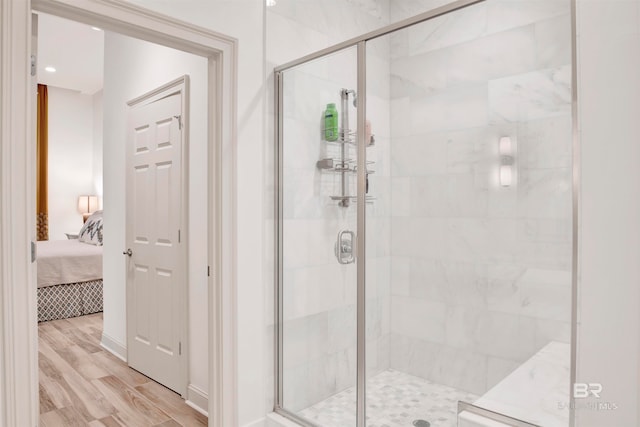 bathroom with a shower with shower door and hardwood / wood-style floors