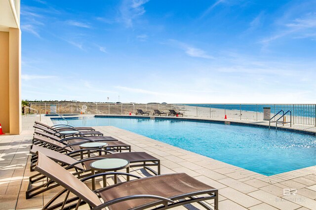 view of pool with a water view and a patio area