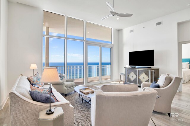 living room featuring light hardwood / wood-style floors, ceiling fan, and expansive windows