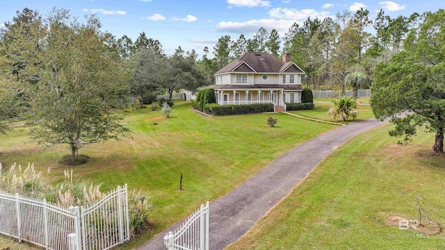 exterior space with fence, aphalt driveway, a front yard, a chimney, and covered porch