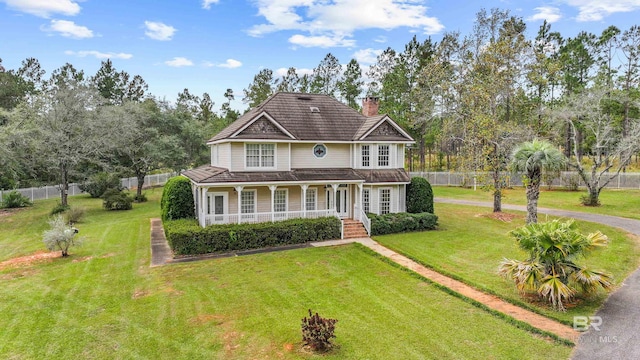 view of front of property with a porch, fence, a chimney, and a front yard