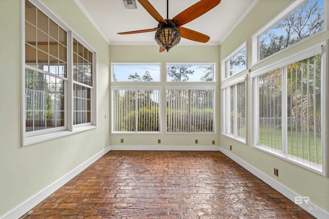 unfurnished sunroom featuring crown molding, baseboards, visible vents, and brick floor