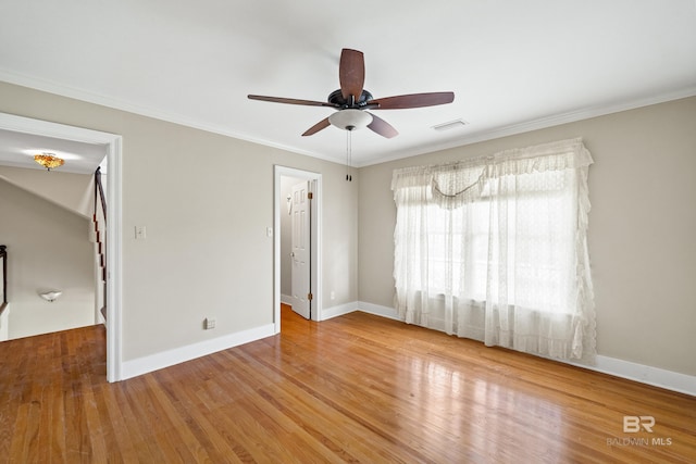 spare room featuring crown molding, ceiling fan, visible vents, and wood finished floors
