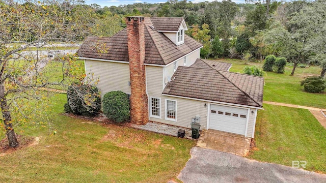 view of front of house featuring an attached garage, a chimney, a front lawn, and aphalt driveway