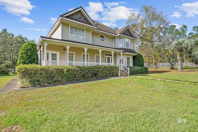 victorian home featuring fence, covered porch, and a front lawn