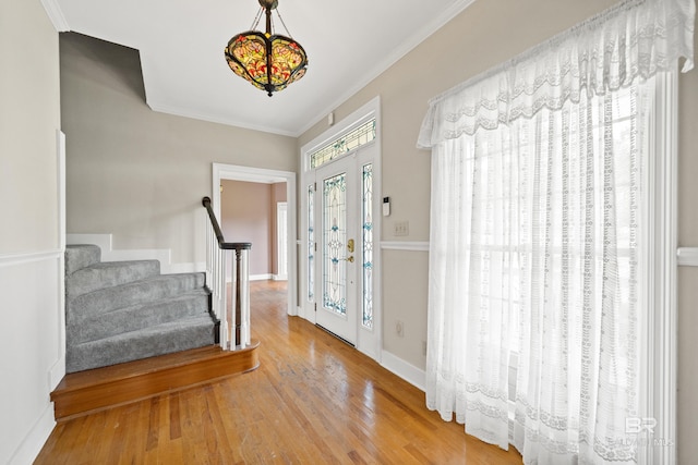 foyer entrance featuring crown molding, baseboards, stairs, and wood finished floors