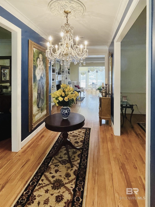 hall featuring hardwood / wood-style floors, an inviting chandelier, and crown molding